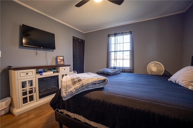 bedroom with a ceiling fan, wood finished floors, and ornamental molding