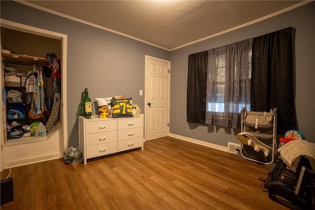 interior space featuring visible vents, crown molding, baseboards, and wood finished floors