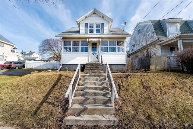 bungalow-style house featuring stairway, a front yard, and fence