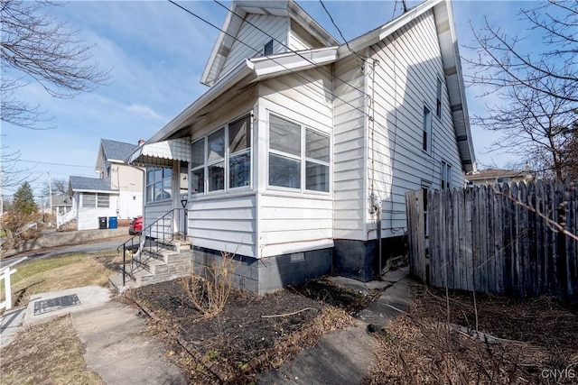 view of side of home featuring crawl space, a sunroom, entry steps, and fence