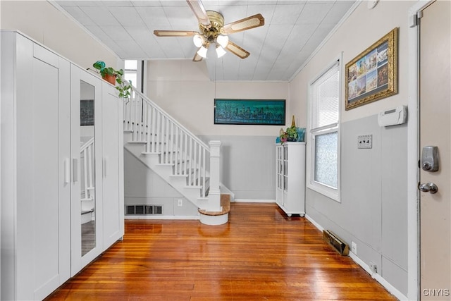 foyer featuring visible vents, crown molding, ceiling fan, stairway, and wood finished floors