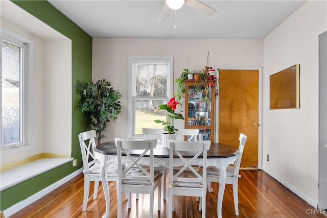 dining space featuring baseboards, wood finished floors, and a ceiling fan