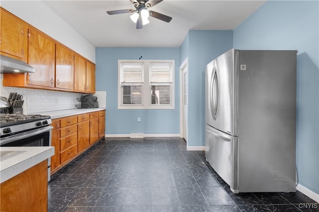 kitchen featuring backsplash, under cabinet range hood, light countertops, brown cabinets, and stainless steel appliances