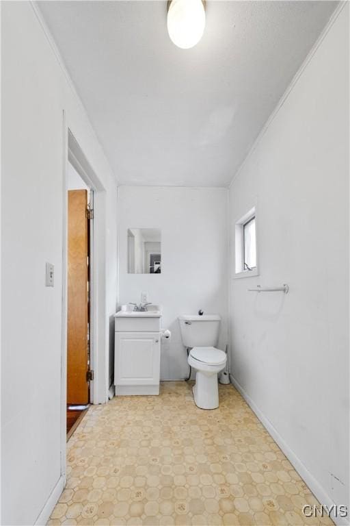 bathroom with tile patterned floors, toilet, ornamental molding, baseboards, and vanity