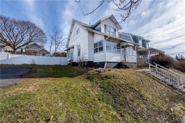 view of side of home with a yard, fence, and central AC