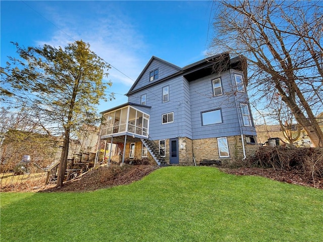 back of house featuring stone siding, a yard, and a sunroom