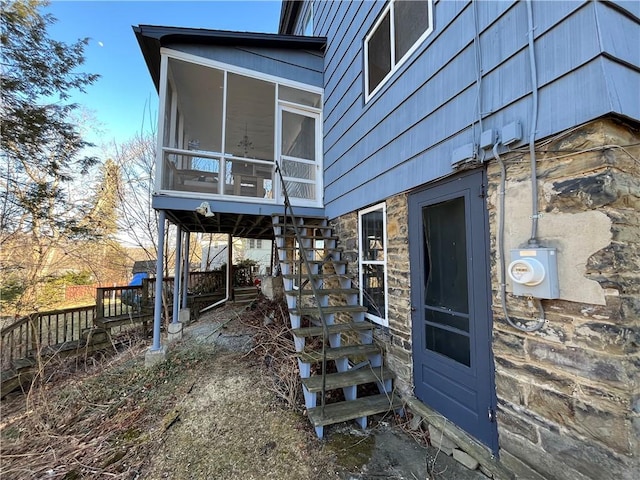 view of property exterior with fence, stone siding, and a sunroom