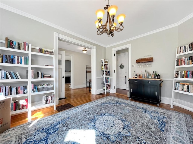 sitting room with a notable chandelier, wood finished floors, baseboards, and ornamental molding