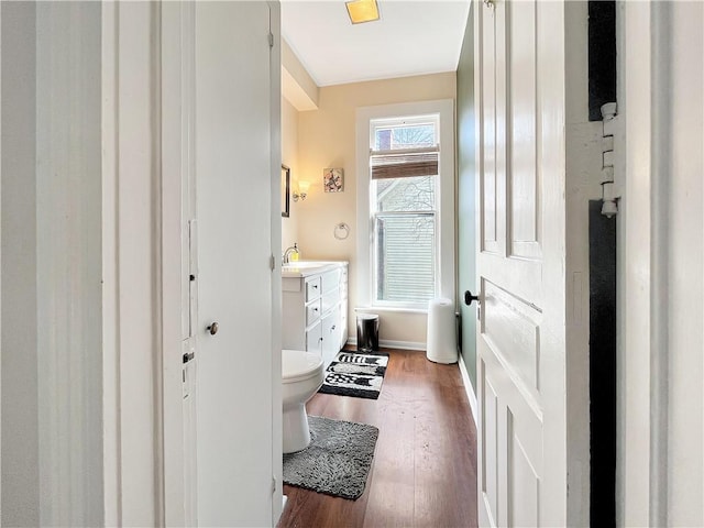 bathroom with baseboards, toilet, wood finished floors, and vanity