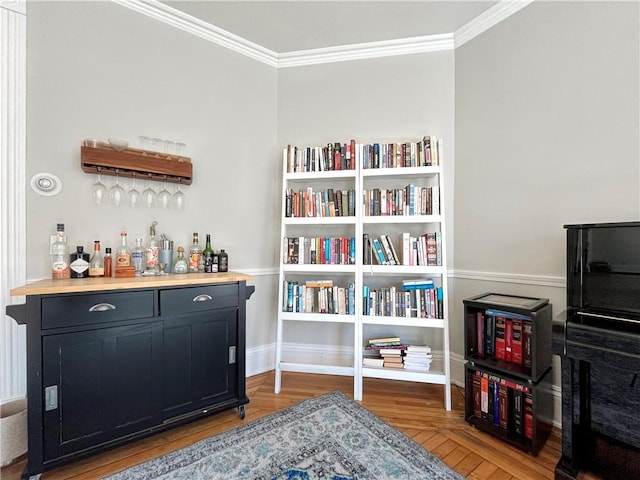 bar with a bar, crown molding, baseboards, and wood finished floors