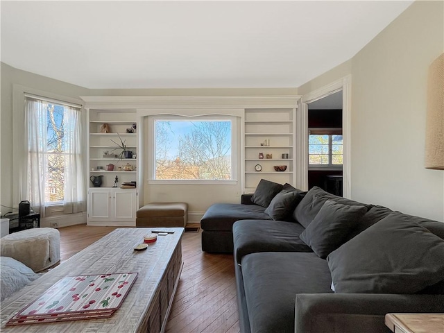 living area featuring built in shelves and hardwood / wood-style floors