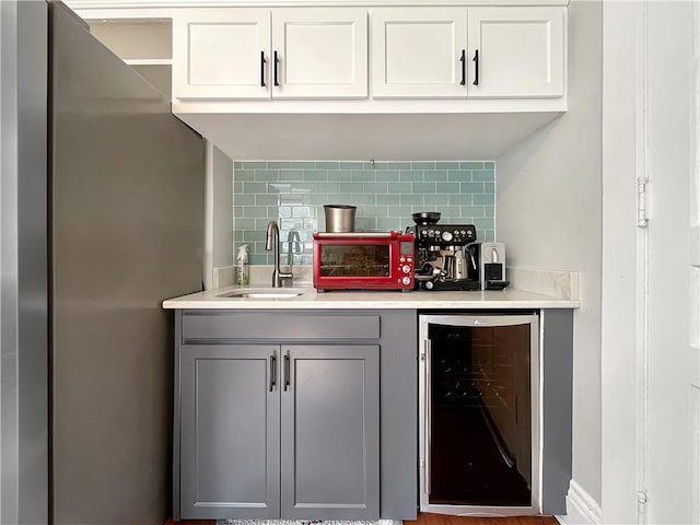 bar with a sink, tasteful backsplash, freestanding refrigerator, wine cooler, and a toaster