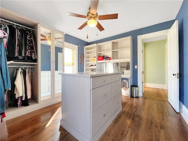 walk in closet with ceiling fan and dark wood-style flooring