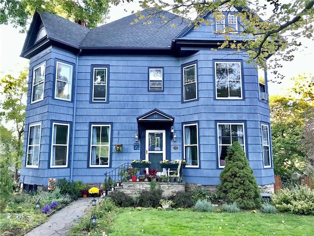 view of front of property with a shingled roof, a front lawn, and a chimney