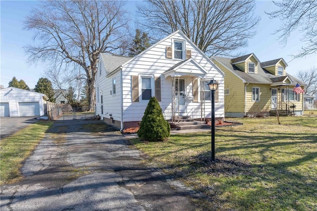 bungalow featuring fence, roof with shingles, an outdoor structure, a front lawn, and a detached garage