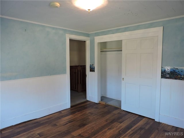 unfurnished bedroom with dark wood finished floors, a wainscoted wall, a closet, and ornamental molding