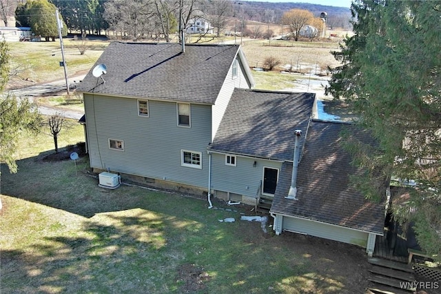 back of property with entry steps, a yard, and a shingled roof