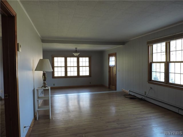 unfurnished living room with a baseboard heating unit, crown molding, wood finished floors, and baseboards