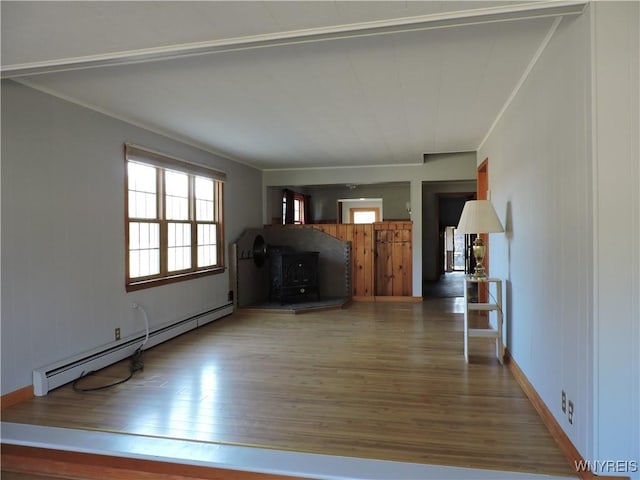 unfurnished living room featuring baseboard heating, wood finished floors, and crown molding