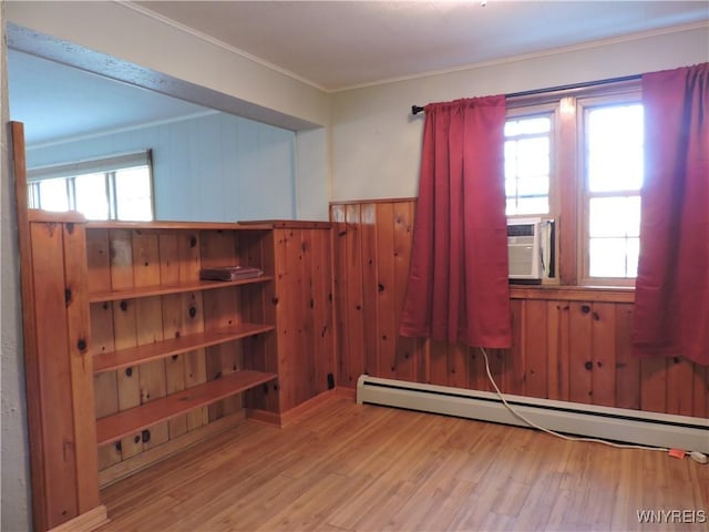 unfurnished room featuring plenty of natural light, baseboard heating, and wood finished floors