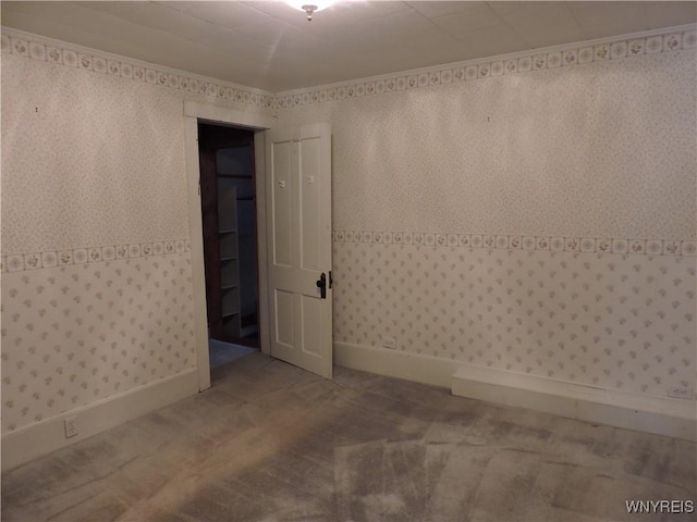 unfurnished room with baseboards, wood finished floors, crown molding, and wallpapered walls