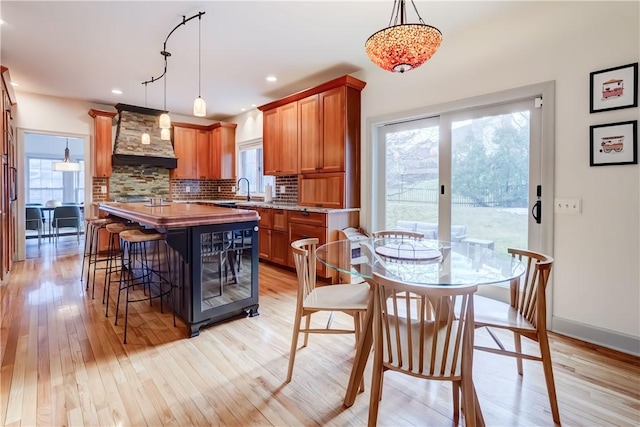 kitchen featuring a wealth of natural light, custom range hood, light wood-style floors, and backsplash