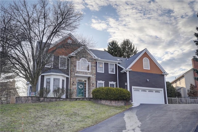 view of front of house featuring a front lawn, driveway, stone siding, fence, and a garage