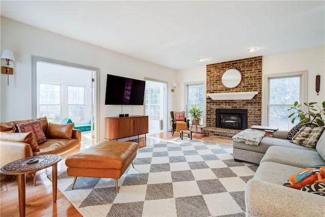 living room with light wood-type flooring, plenty of natural light, and a brick fireplace