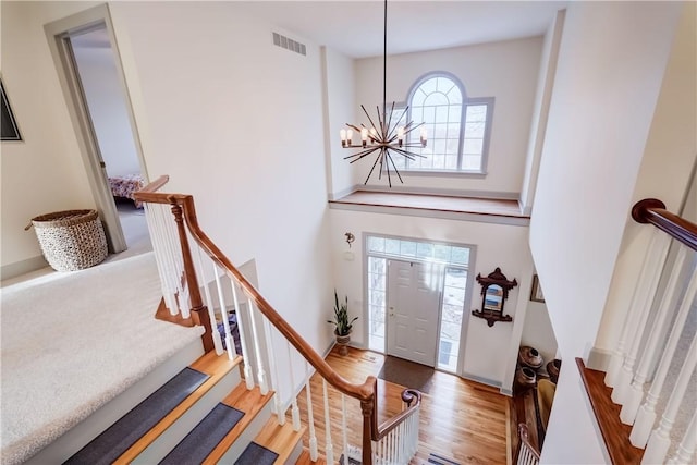 foyer featuring a notable chandelier, visible vents, stairway, and wood finished floors