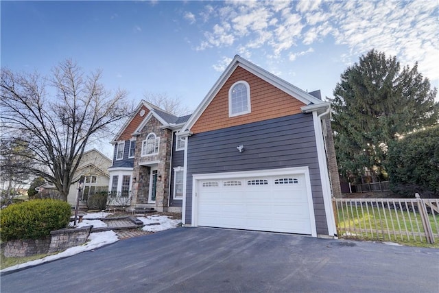 traditional-style house with aphalt driveway, stone siding, a garage, and fence