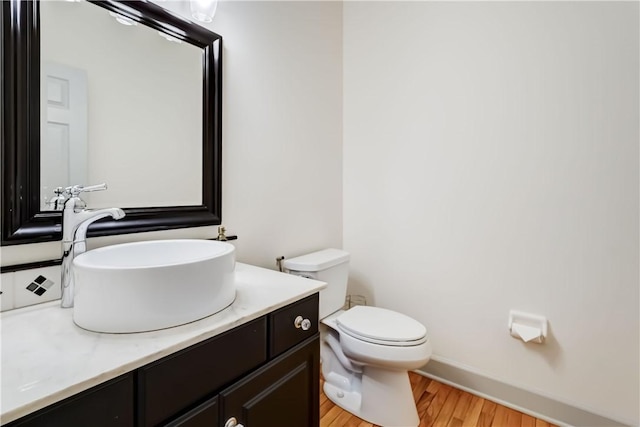 bathroom featuring toilet, vanity, and wood finished floors