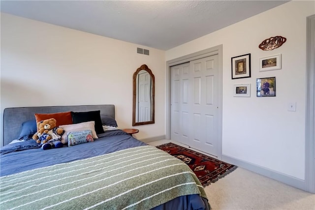 carpeted bedroom featuring a closet, visible vents, and baseboards