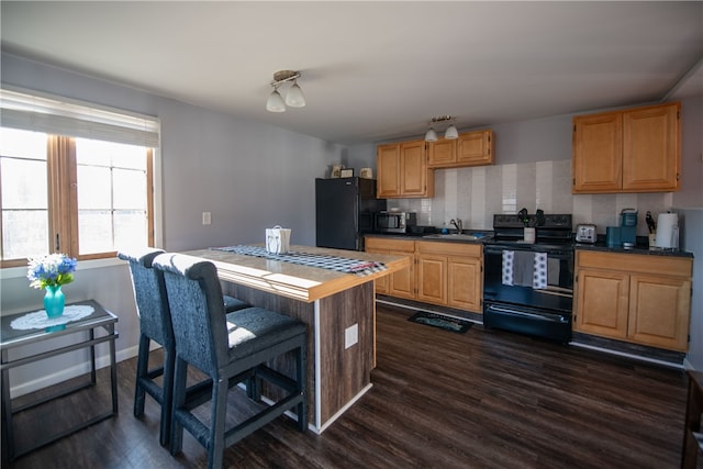 kitchen with a sink, black appliances, dark wood-type flooring, dark countertops, and tasteful backsplash