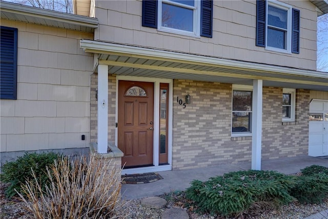 property entrance with a porch, brick siding, and a garage