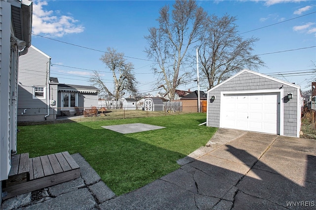 view of yard with concrete driveway, an outbuilding, fence, and a detached garage