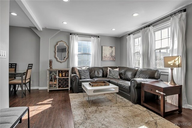 living room featuring dark wood finished floors, beamed ceiling, baseboards, and a wealth of natural light