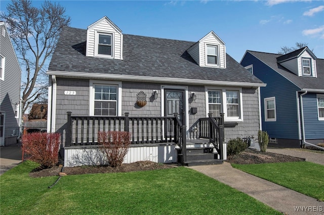 cape cod home featuring a front yard and a shingled roof