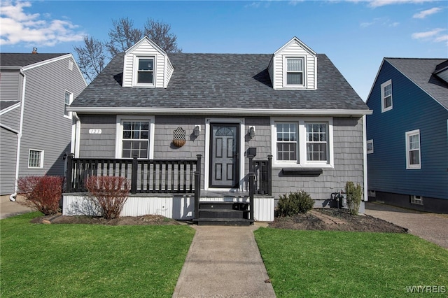 new england style home featuring a front lawn and roof with shingles