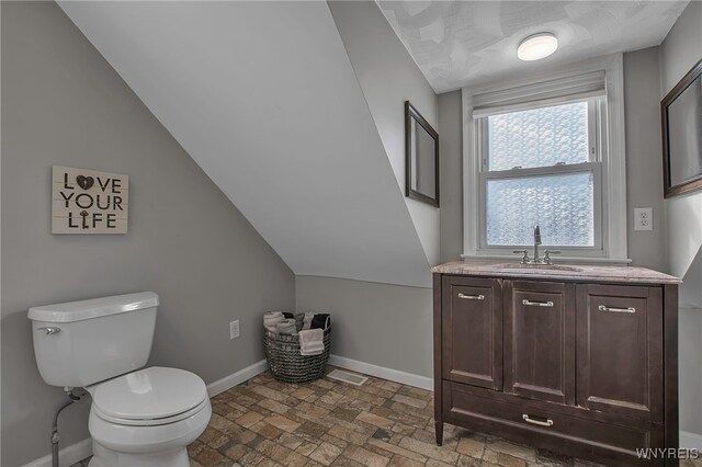 bathroom with vanity, visible vents, baseboards, vaulted ceiling, and toilet