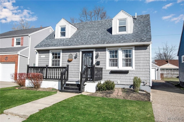 cape cod-style house featuring a shingled roof and a front yard