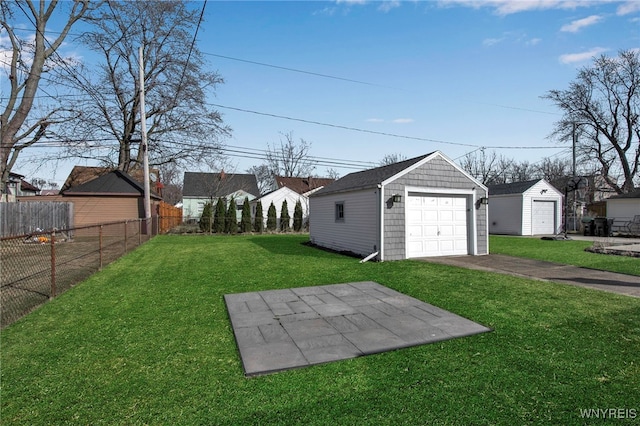 view of yard featuring aphalt driveway, an outbuilding, a garage, and fence