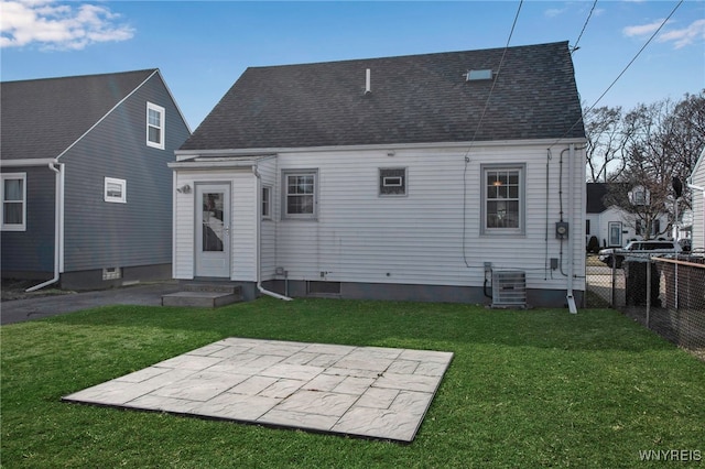 back of property with fence, a yard, a shingled roof, central air condition unit, and a patio area