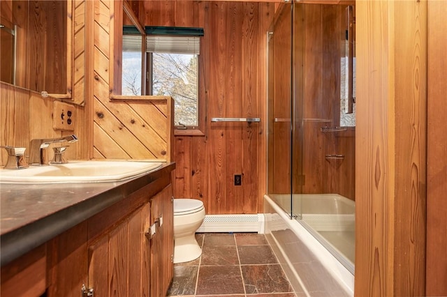 bathroom with toilet, wood walls, a baseboard radiator, enclosed tub / shower combo, and vanity