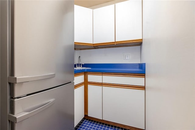 kitchen featuring white cabinets, freestanding refrigerator, and a sink