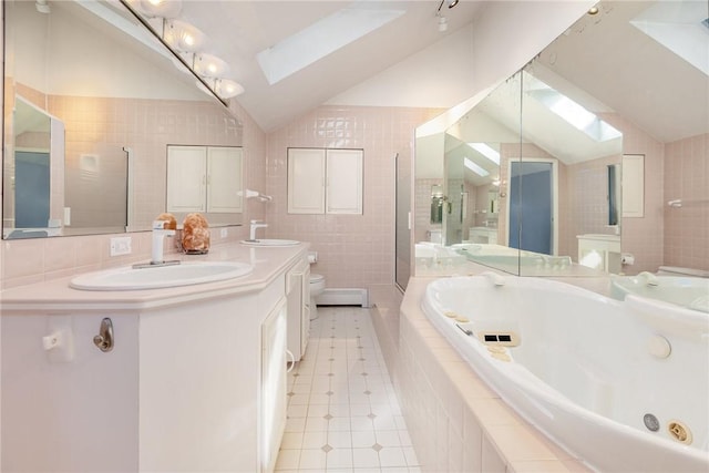 full bathroom featuring toilet, vaulted ceiling with skylight, a tub with jets, tile walls, and a sink