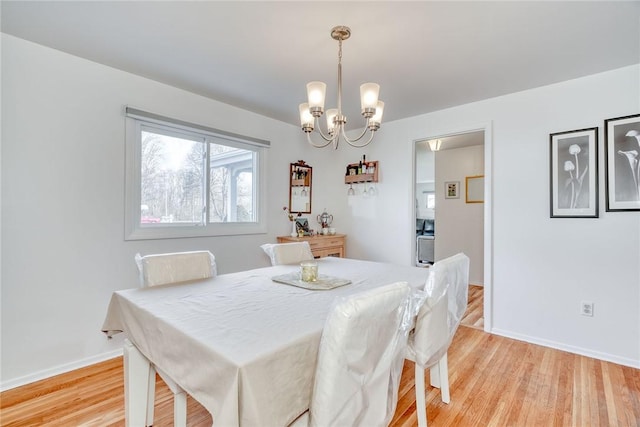 dining space featuring a notable chandelier, light wood-style flooring, and baseboards