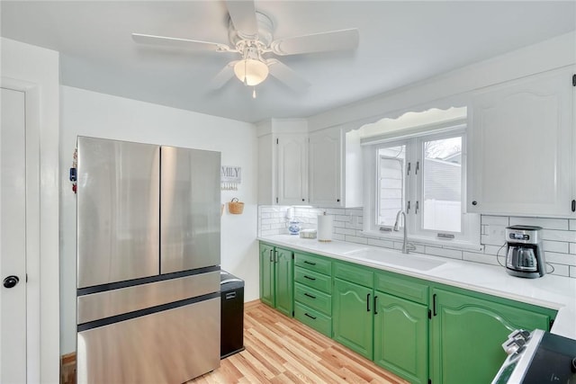 kitchen with a sink, green cabinetry, light countertops, and freestanding refrigerator