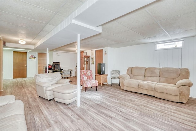 living room featuring light wood-type flooring and a paneled ceiling