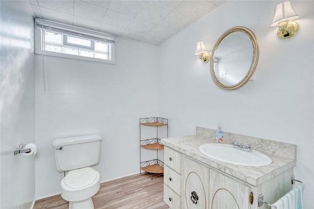 half bath with vanity, toilet, and wood finished floors