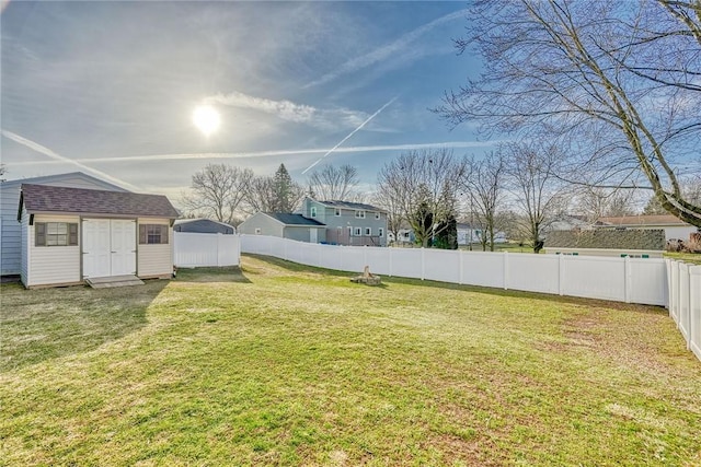 view of yard with a fenced backyard, a storage unit, and an outdoor structure